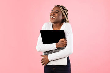 Excited black woman hugging personal computer at studio