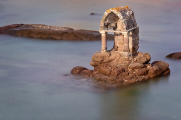 Statue of Saint Guirec at high tide on the beach of Ploumanach in Perros-Guirec, Côtes d'Armor,...