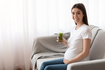Vitamins During Pregnancy. Young Pregnant Woman Drinking Green Smoothie While Relaxing On Couch