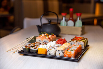 rolls on a black square plate and a teapot of tea