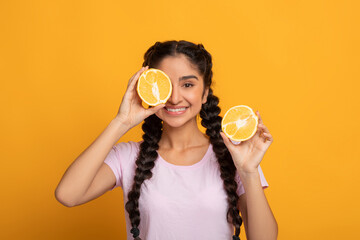 Indian lady covering eyes with halves of citrus orange fruit