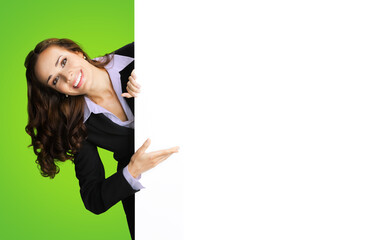 Happy excited smiling woman in black confident suit showing white banner signboard. Business and advertising concept. Copy space empty place for text. Green color background..