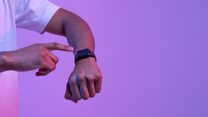 Fototapeta premium African Male Using Smartwatch With Black Blank Screen Under Purple Neon Light