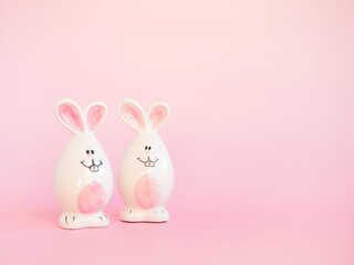 Cute white ceramic easter bunnies or rabbits on pink background. Minimal Holiday concept. Symbol Happy Easter holiday. Creative. Copy space