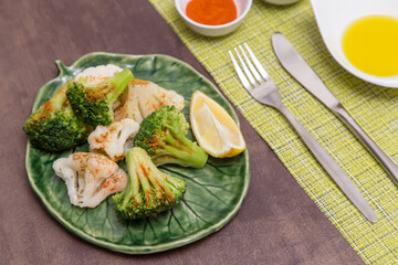 Broccoli and cauliflower with spices and lemon on green plate. Vegan vegetarian healthy diet food concept