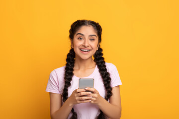 Indian woman using smartphone isolated on yellow background