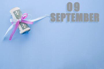 calendar date on blue background with rolled up dollar bills pinned by blue and pink ribbon with...