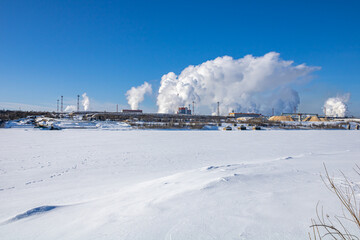 A large industrial complex against the backdrop of a bright blue sky.