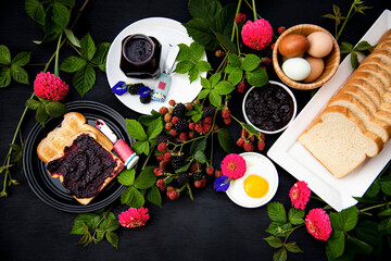 Toasted Spread With Homemade Organic Blackberry Jam, Hard boild eggs, and Fried egg on Black Background.