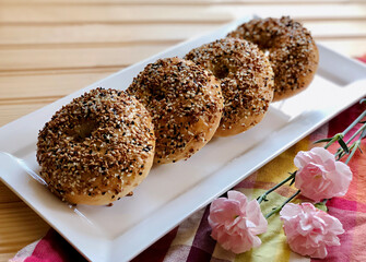 Homemade Everything Bagels on White Plate on Wood Background