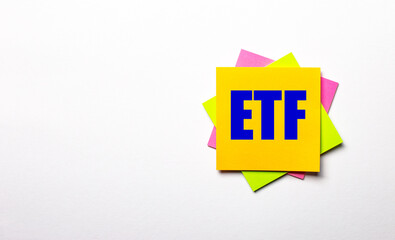 On a light background - bright multicolored stickers with the text ETF Exchange Traded Funds. Copy space