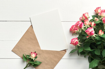 Greeting card mockup with fresh roses on white wooden background