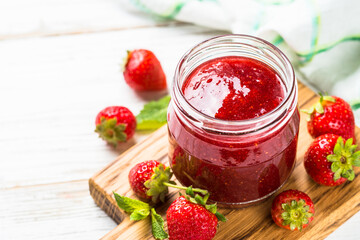 Strawberry jam in the glass jar with fresh berries. Close up.