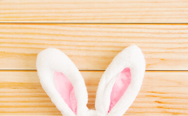 Symbol of Holy Easter. White bunny ears on a light wooden background. Top view. Copy space. Easter background. Background for design.