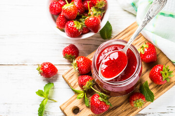 Strawberry jam in the glass jar with fresh berries at white. Top view with copy space