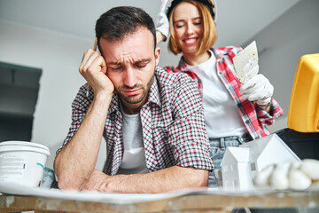 Woman painter leaning over a drowsy civil engineer