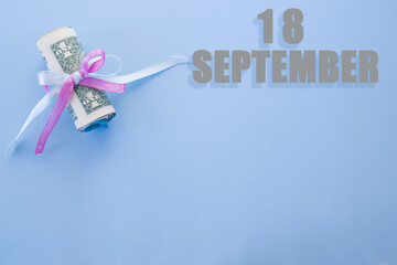 calendar date on blue background with rolled up dollar bills pinned by blue and pink ribbon with...