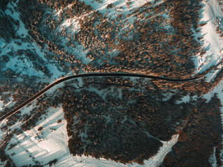 Top aerial view on mountains road. Snow mountain landscape. Teal and orange