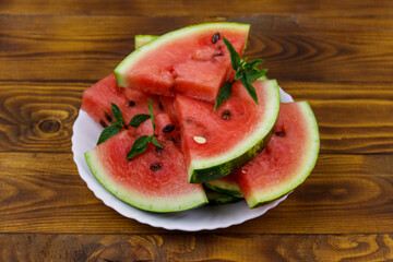 Fresh ripe sliced watermelon in white plate on a wooden table