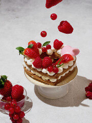 Levitation from berries, food. The heart-shaped layer cake is decorated with fresh berries, chocolate and flowers. Cake with fresh strawberries, raspberries and red currants. Dessert with red berries.