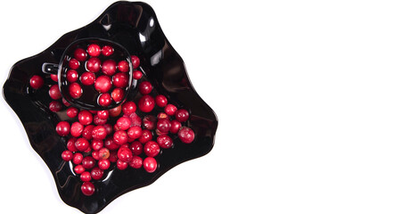 Close up of cranberries on black plate and cranberry juice in cup  isolated on white background.