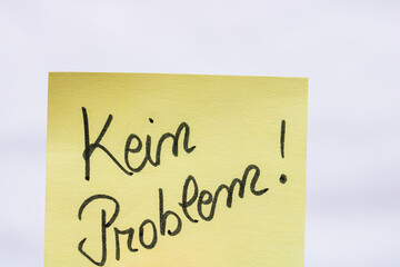 Kein problem (no problem)  handwriting text close up isolated on yellow paper with copy space.