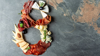 Antipasto or Italian appetizers set with gourmet food on stone table. Mixed cheese and meat snacks of the number eight. International Women's Day. top view