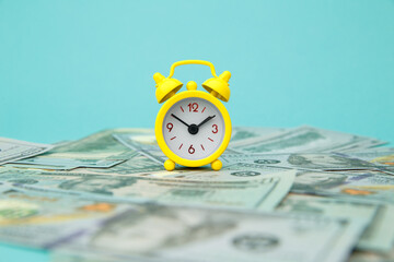 Close-up of yellow alarm clock and money on blue background. Business Finance and Money concept....