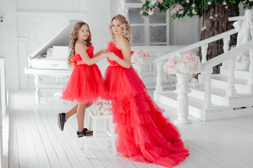 woman with daughter in  dresses.Mom and her child outdoors. Happy family.Beautiful mother and daughter in elegant airy pink dresses with a train in the photo studio.The concept of family love