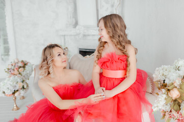 woman with daughter in  dresses.Mom and her child outdoors. Happy family.Beautiful mother and daughter in elegant airy pink dresses with a train in the photo studio.The concept of family love