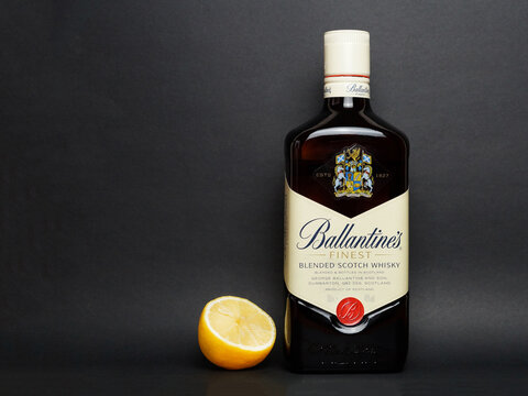 Ballantine's scotch whiskey bottle and half lemon on black background