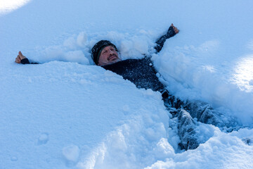 Naklejka na ściany i meble man lying in deep snow in winter season