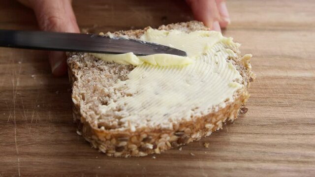 The butter is spread over the bread with a knife.