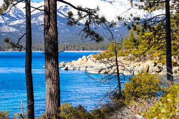 a stunning shot of the vast clear blue lake water with snow capped mountain ranges and lush green...