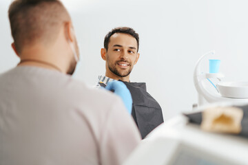 Male Dentist discussing with happy patient after treatment