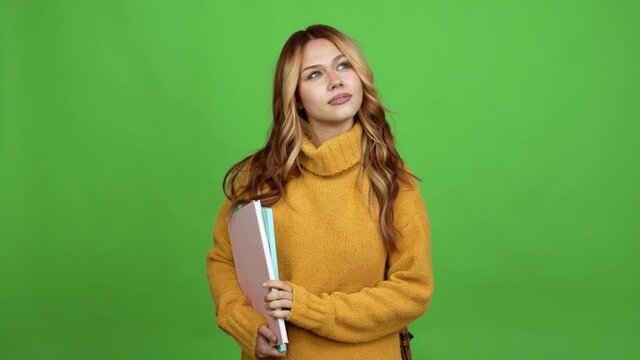 Teenager woman with backpack looking up over isolated background chroma key