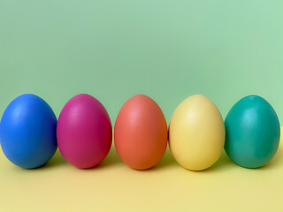 Colorful Easter eggs.  Bright multi-colored Easter eggs on a light yellow and green background.  Coloring eggs for Easter.  Minimal easter concept.  Copy space for your text