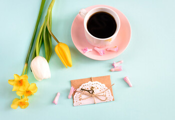 Coffee, gift and yellow tulips bouquet on blue background. Concept of valentines day, birthday, easter, holiday, mother day