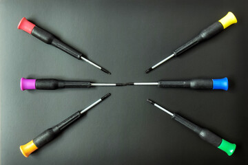 Set of screwdrivers with multi-colored handles on black background. Folded in form of star. Top...