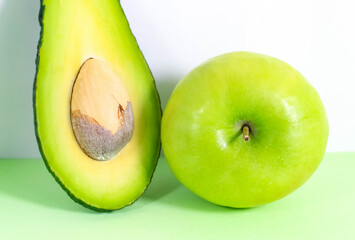 Half an avocado and a whole green apple close-up.
