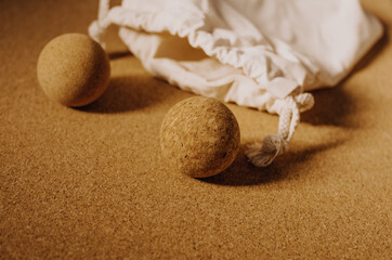 Close up of fascia release cork massage balls with a organic cotton bag on a cork mat background, with warm golden light. Concept: eco friendly and sustainable self care tools, props.