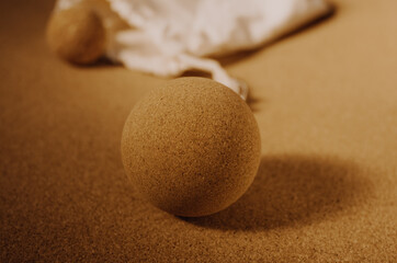 Close up of fascia release cork massage ball on a cork mat background, with warm golden light. Concept: eco friendly and sustainable self care tools, props.
