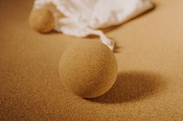 Fototapeta na wymiar Close up of fascia release cork massage ball a cork mat background, warm golden light. Concept: eco friendly and sustainable self care tools, props.
