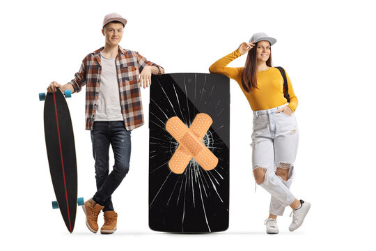 Full length portrait of a guy with a skateboard and female student leaning on a mobile phone with cracked screen and bandage