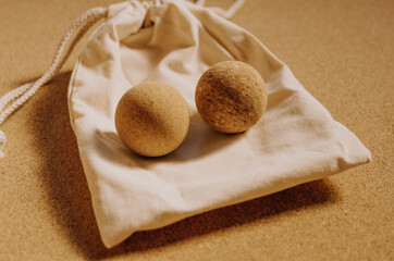 Close up of fascia release cork massage balls on a organic cotton bag on a cork mat background, with warm golden light. Concept: eco friendly and sustainable self care tools, props.