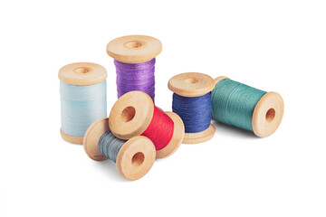 Sewing needle and colorful sewing thread on wooden spool on isolated white background