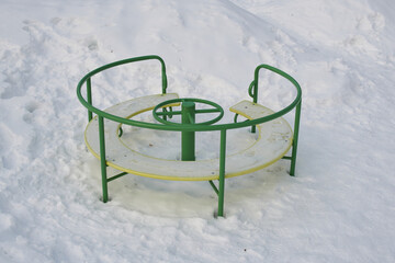 Snow-covered carousel on the playground.