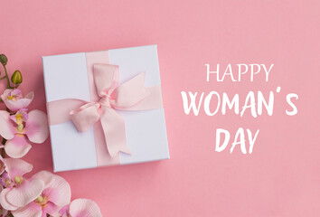 Happy Women's Day text , pink orchids and a gift box on pink background. Happy Women's Day text on pink background.