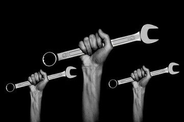 black and white photo. three spanners in the women's hands. hands holds a wrenches on a gray background. Combination wrench. big chrome vanadium spanner in the hand. women's work.