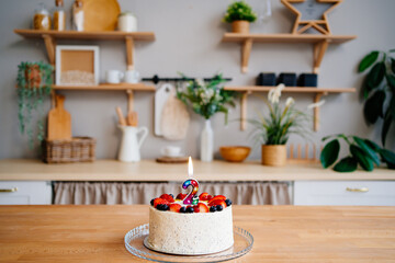 cake with candle number two and fruit on table on Scandinavian-style kitchen 